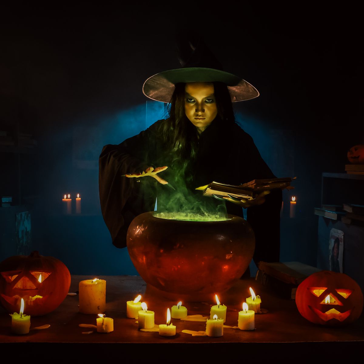 Witch standing behind a bubbling cauldron with candles as the focal point