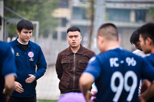 Football players gather for a team discussion on a soccer field in Hanoi, Vietnam.