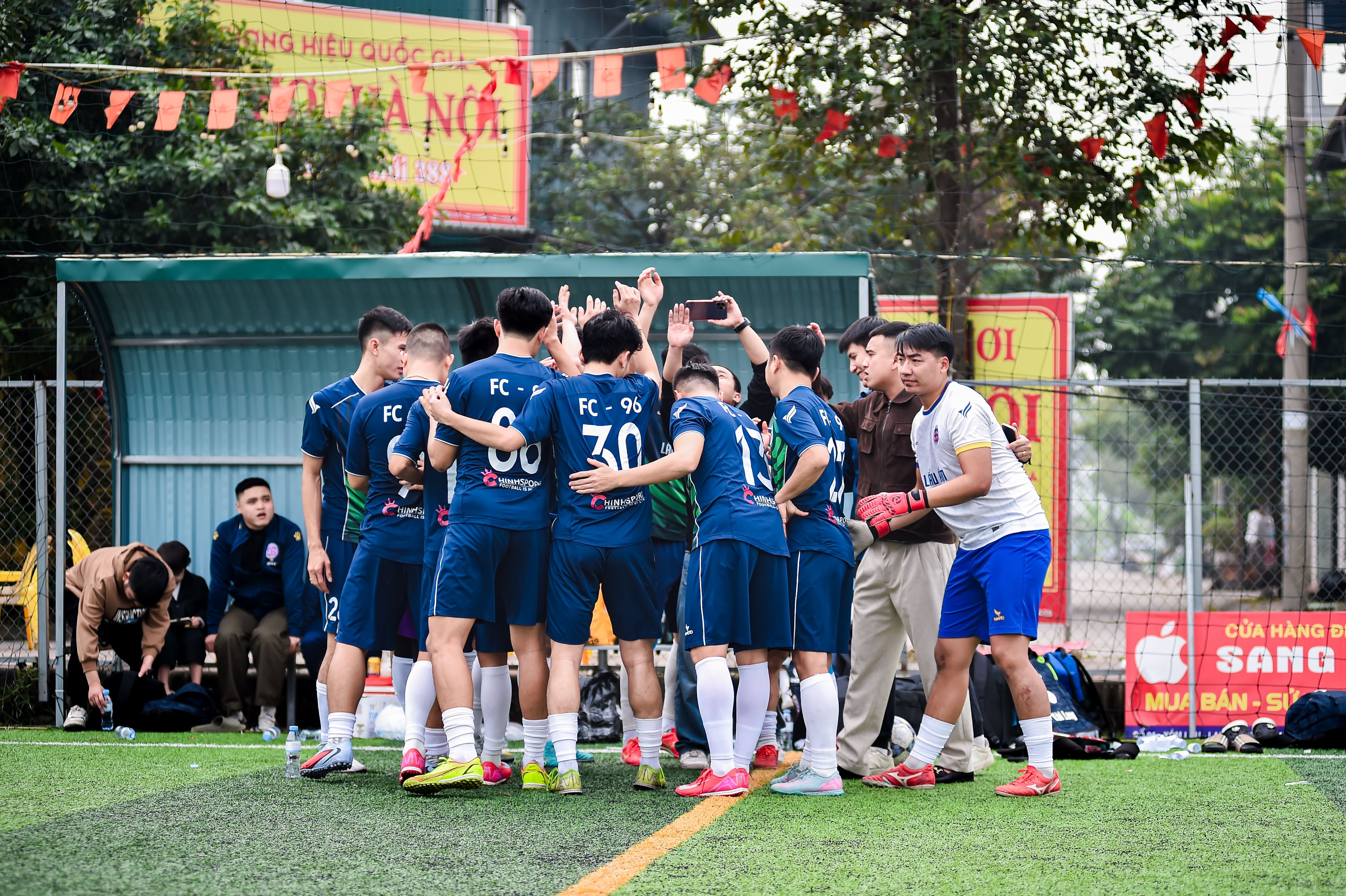 Soccer team of young adults huddling during a match in Hà Nội.
