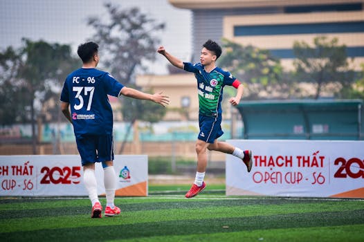 Two soccer players celebrate a goal on a field during a sports event in Hanoi, Vietnam.