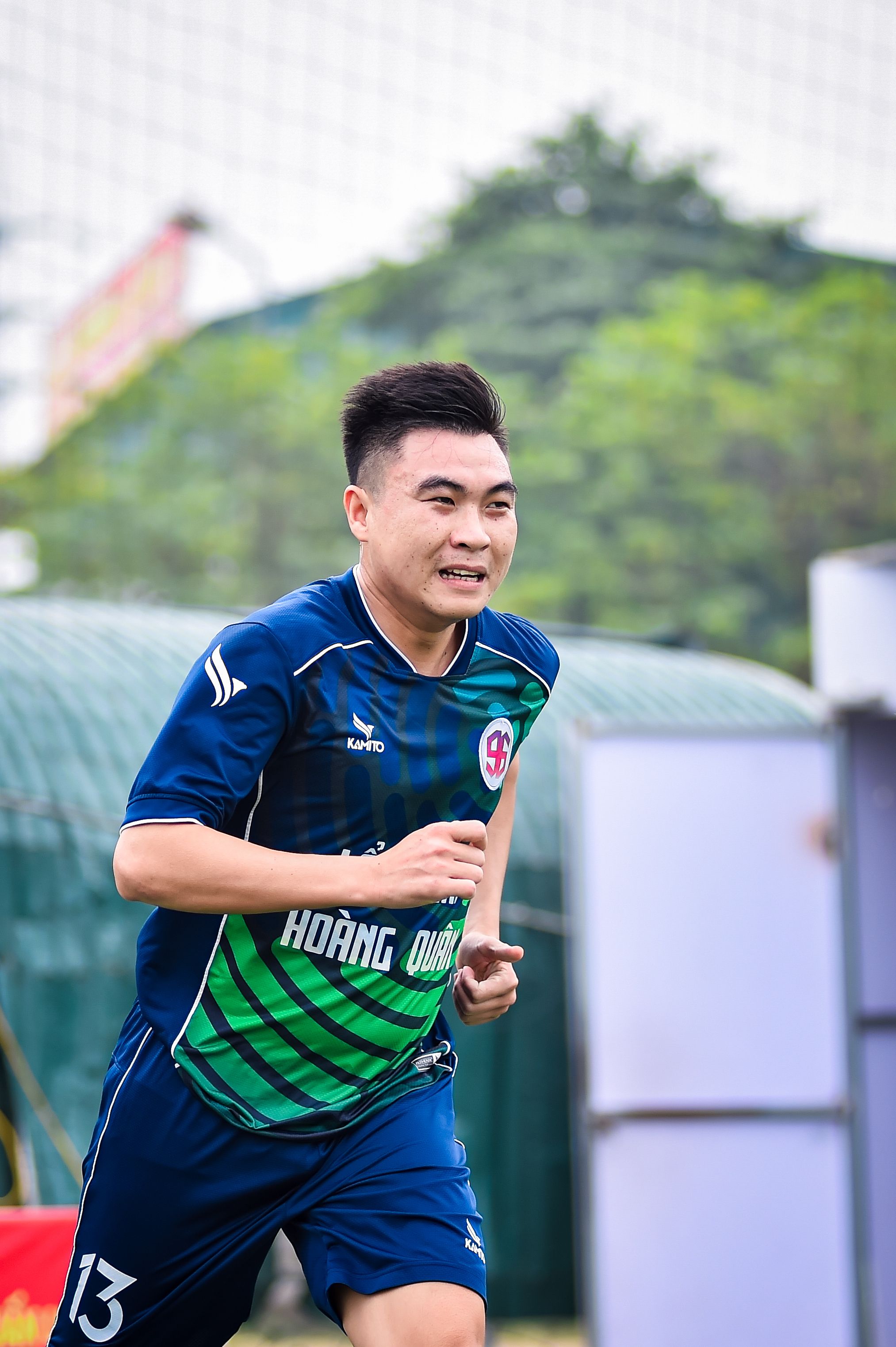 A focused Asian football player running during a game in Hanoi, Vietnam.