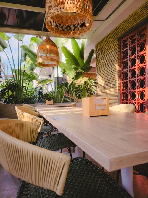 Free Cozy outdoor café seating at a Bucaramanga location featuring warm lighting and lush greenery. Stock Photo