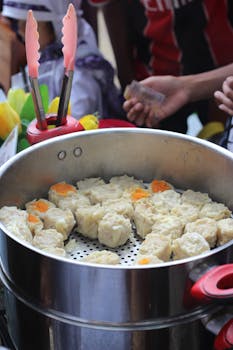 Close-up of freshly steamed dumplings in a traditional street food market setup.