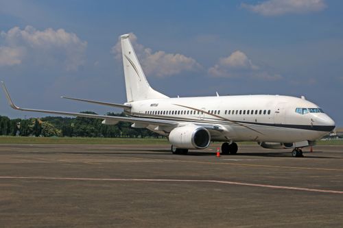 Free A commercial airplane parked on an airport runway with a clear blue sky and grassy background. Stock Photo