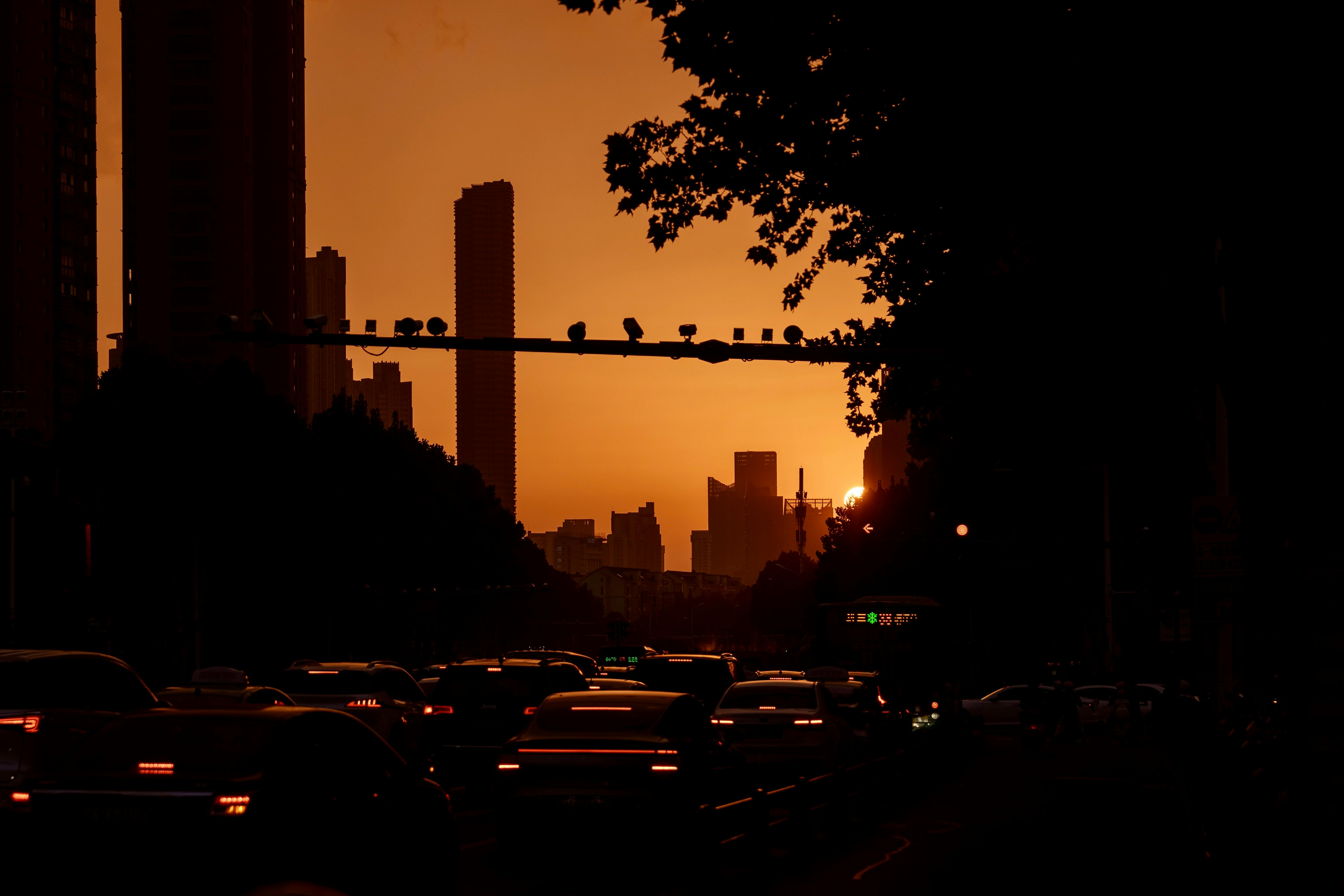 Silhouette of city skyline at sunset with bustling traffic below, warm lighting.