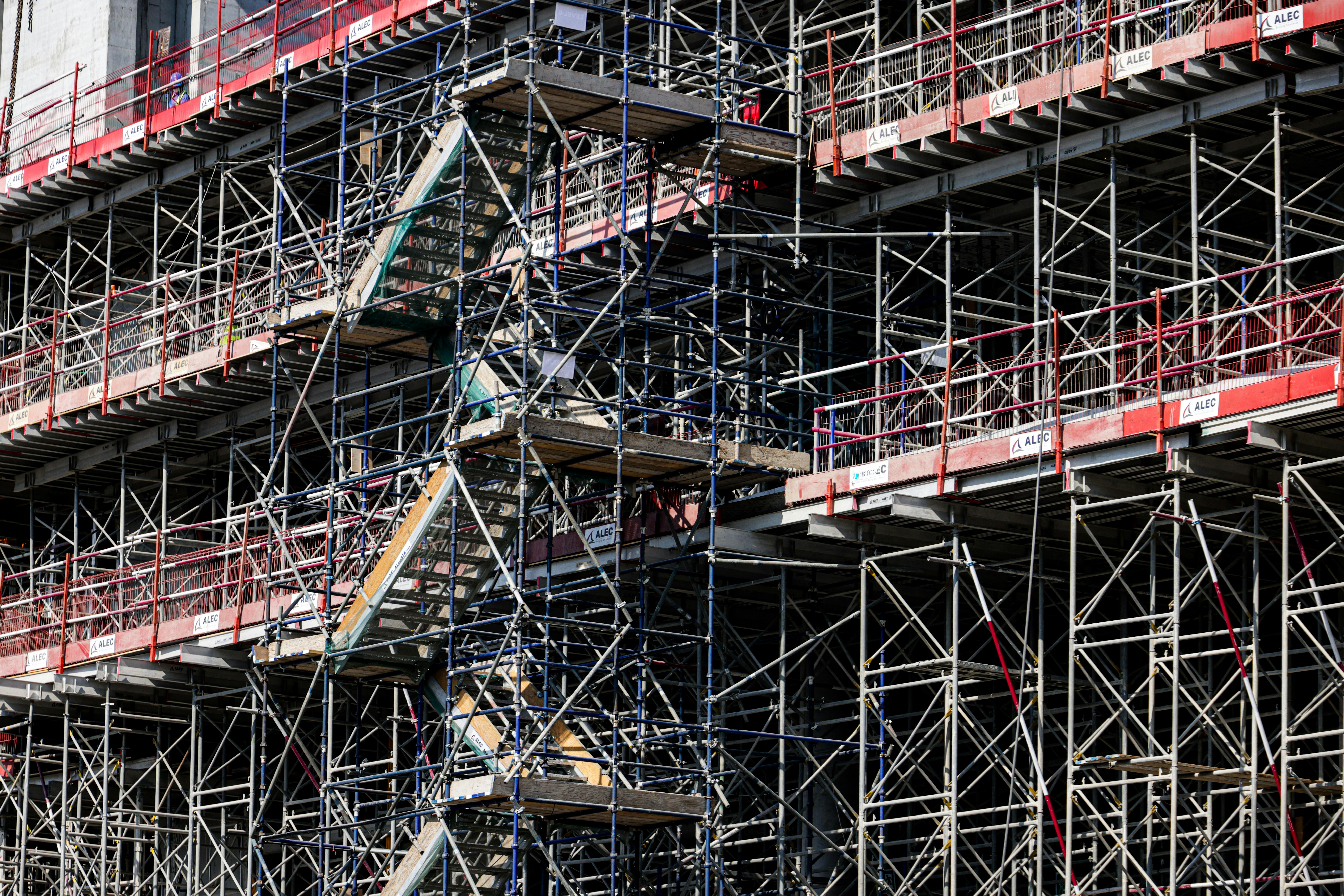 Detailed view of a multi-level scaffolding on a building under construction, shot during daylight.
