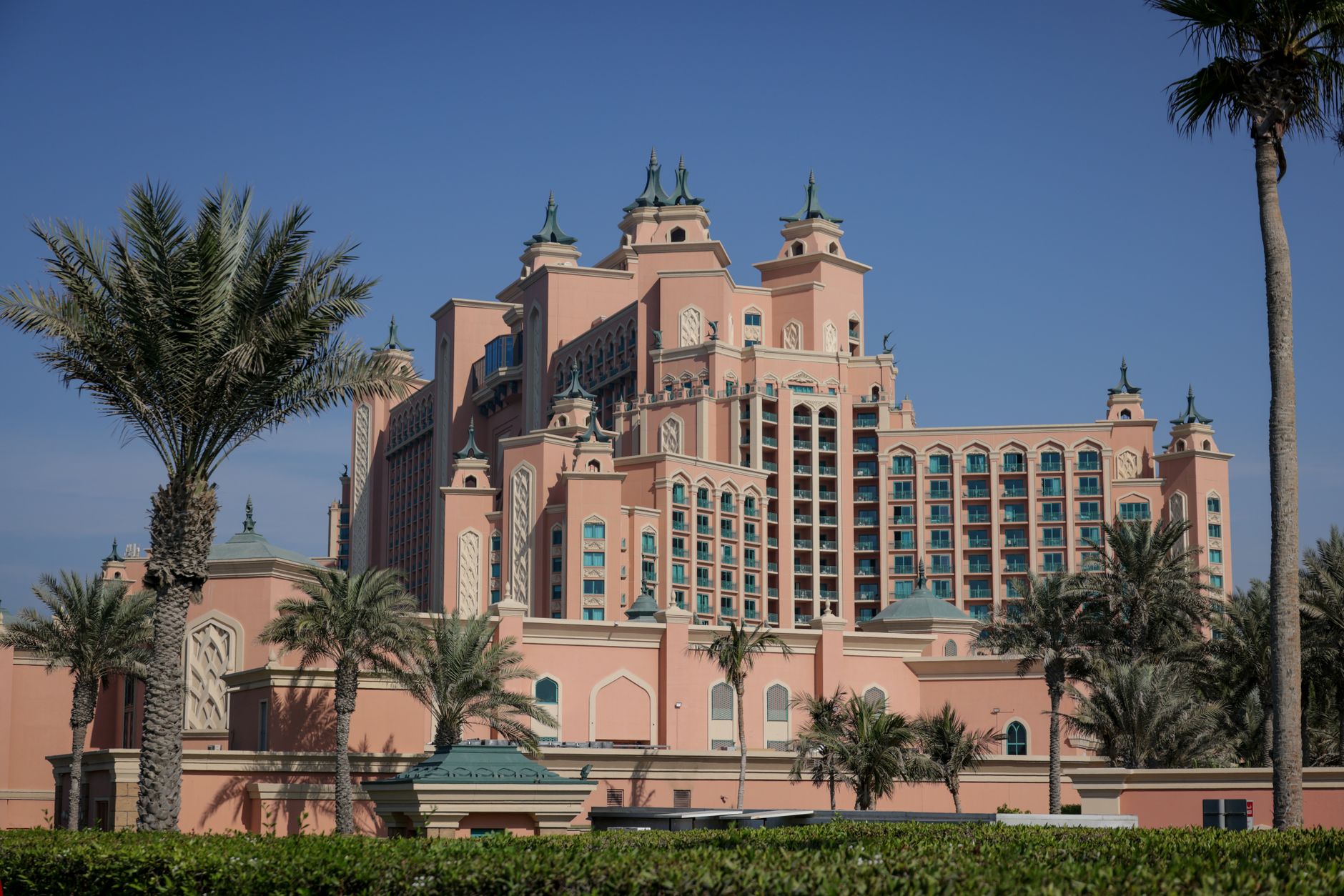 Elegant view of the Atlantis Hotel in Dubai with palm trees under a clear blue sky.