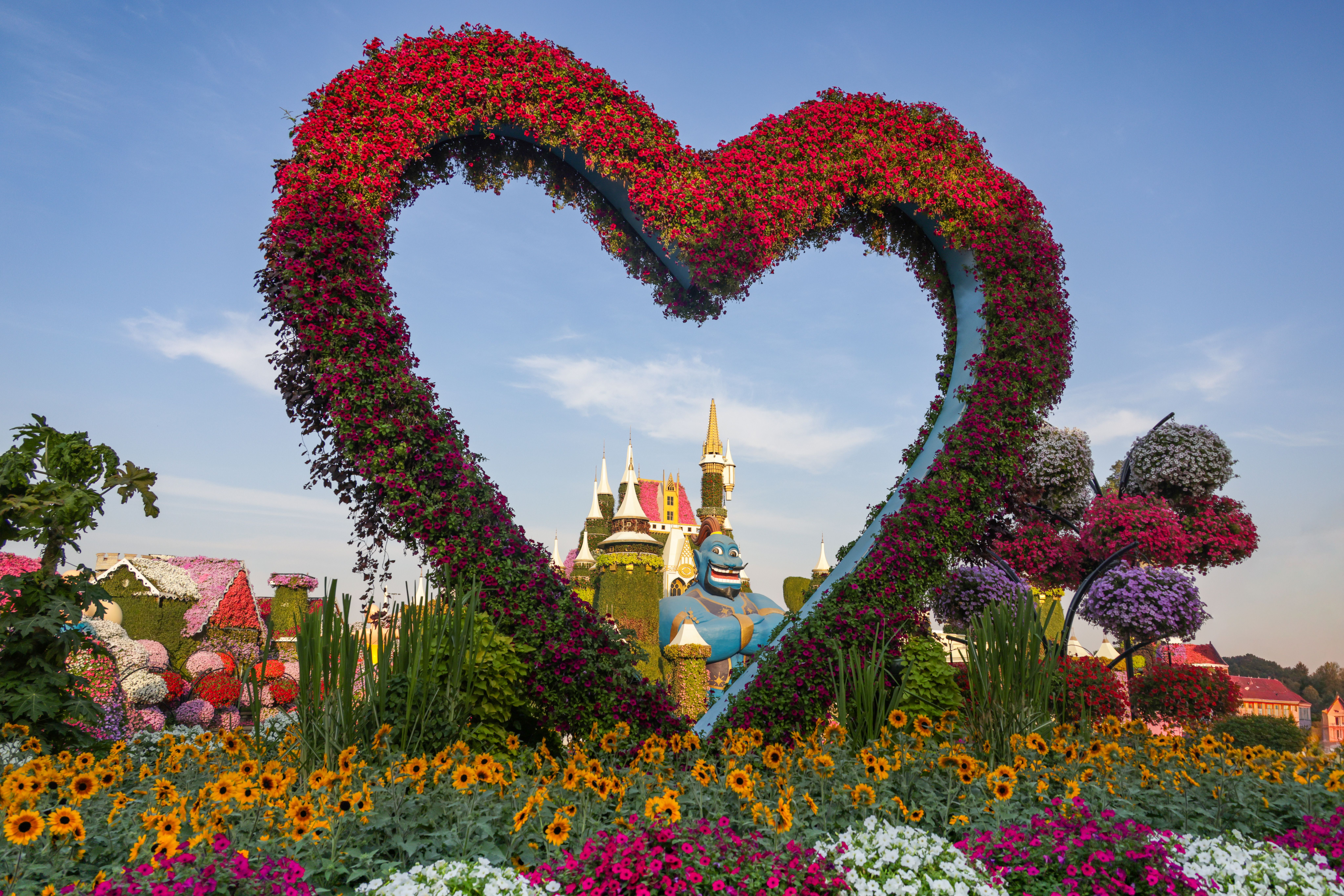 Beautiful garden featuring a heart-shaped floral arch with vibrant blooms and castle backdrop.