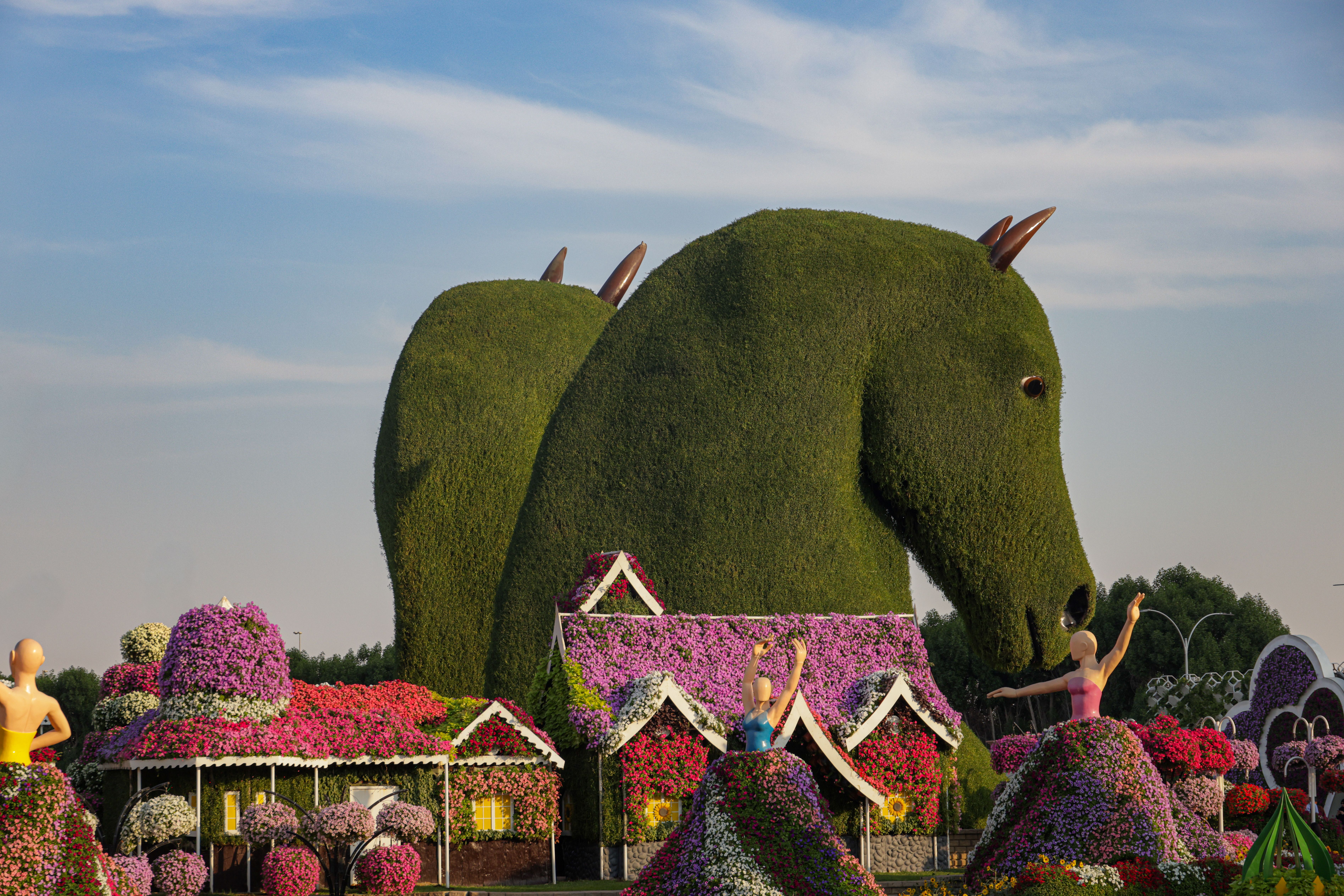 Horse-shaped topiary in a vibrant flower garden with floral structures.