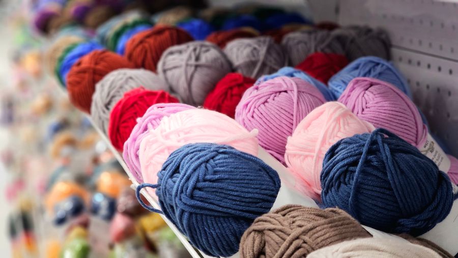 Yarn balls in many colours arranged on a display stand