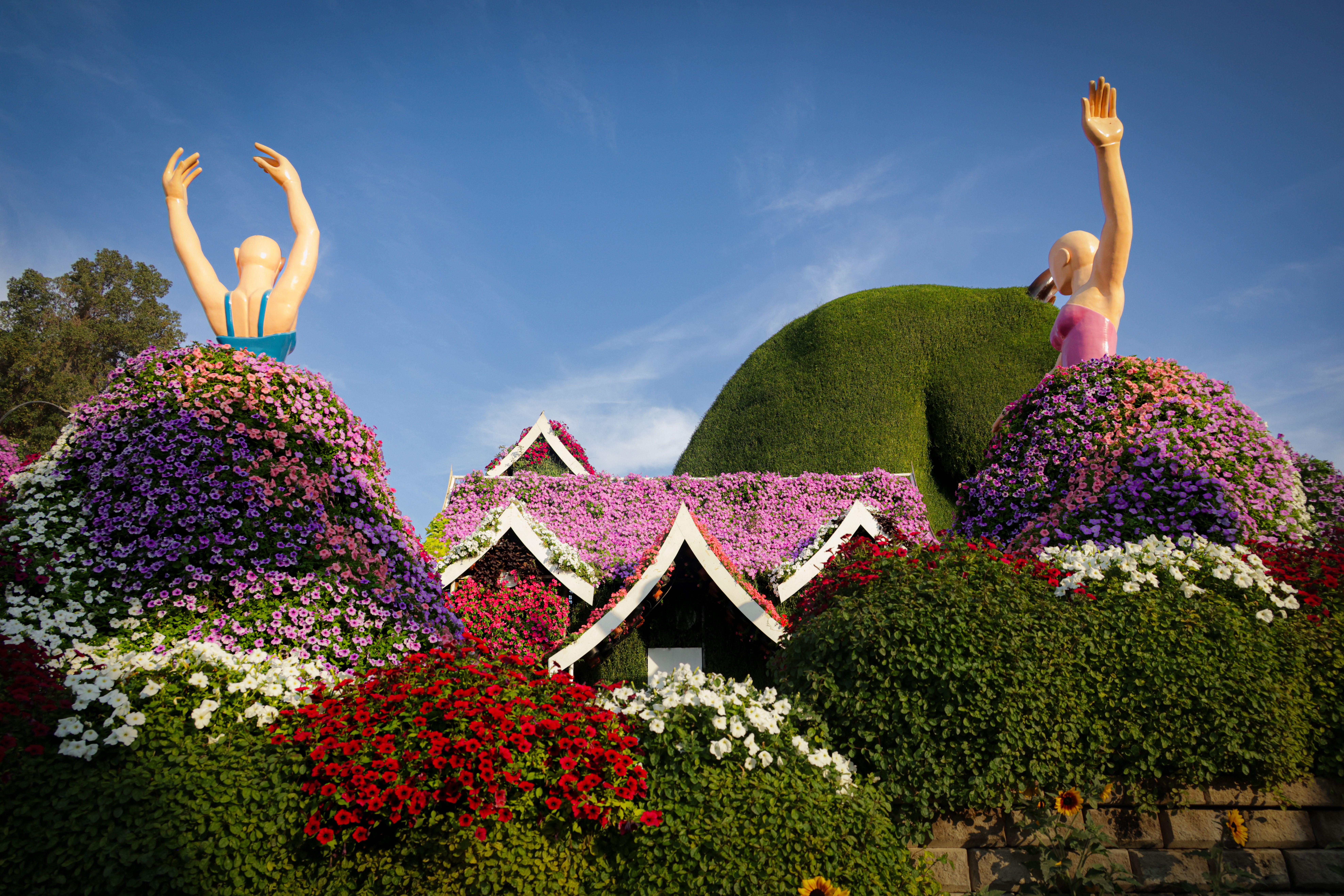 Colorful garden with floral sculptures and vibrant blooms creating a picturesque scene.