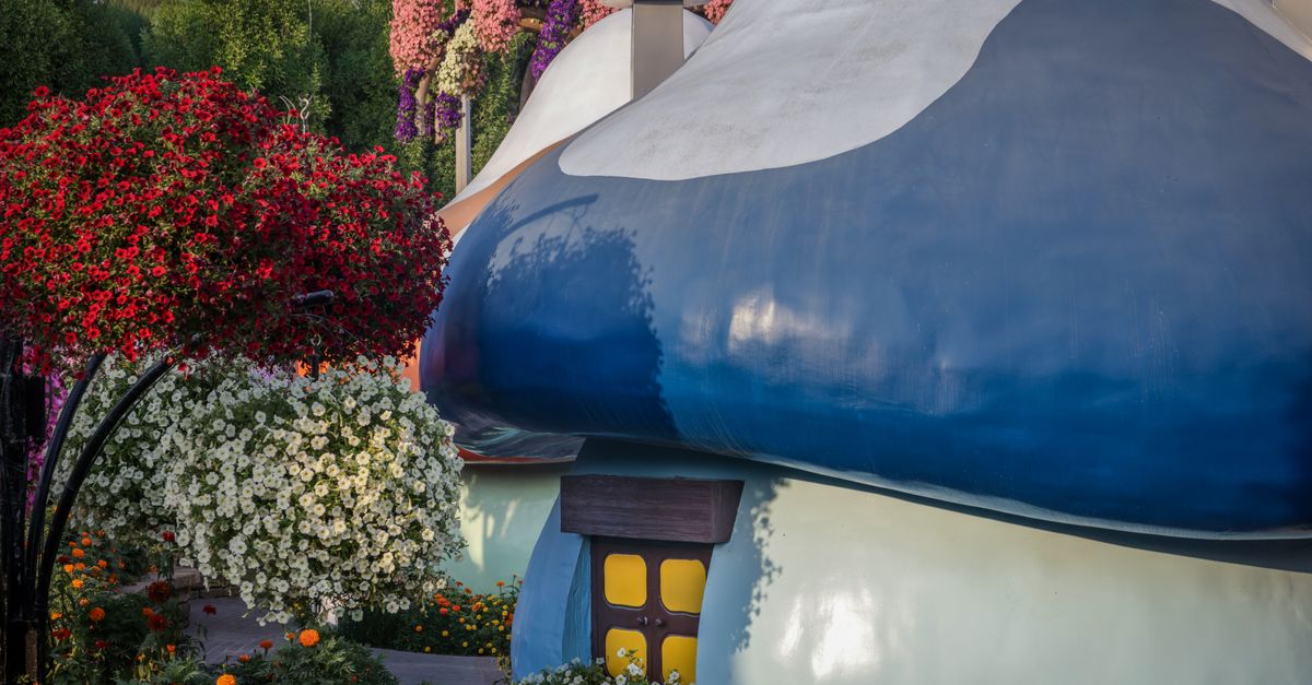 Charming mushroom house surrounded by colorful blooming flowers in a vibrant garden setting.
