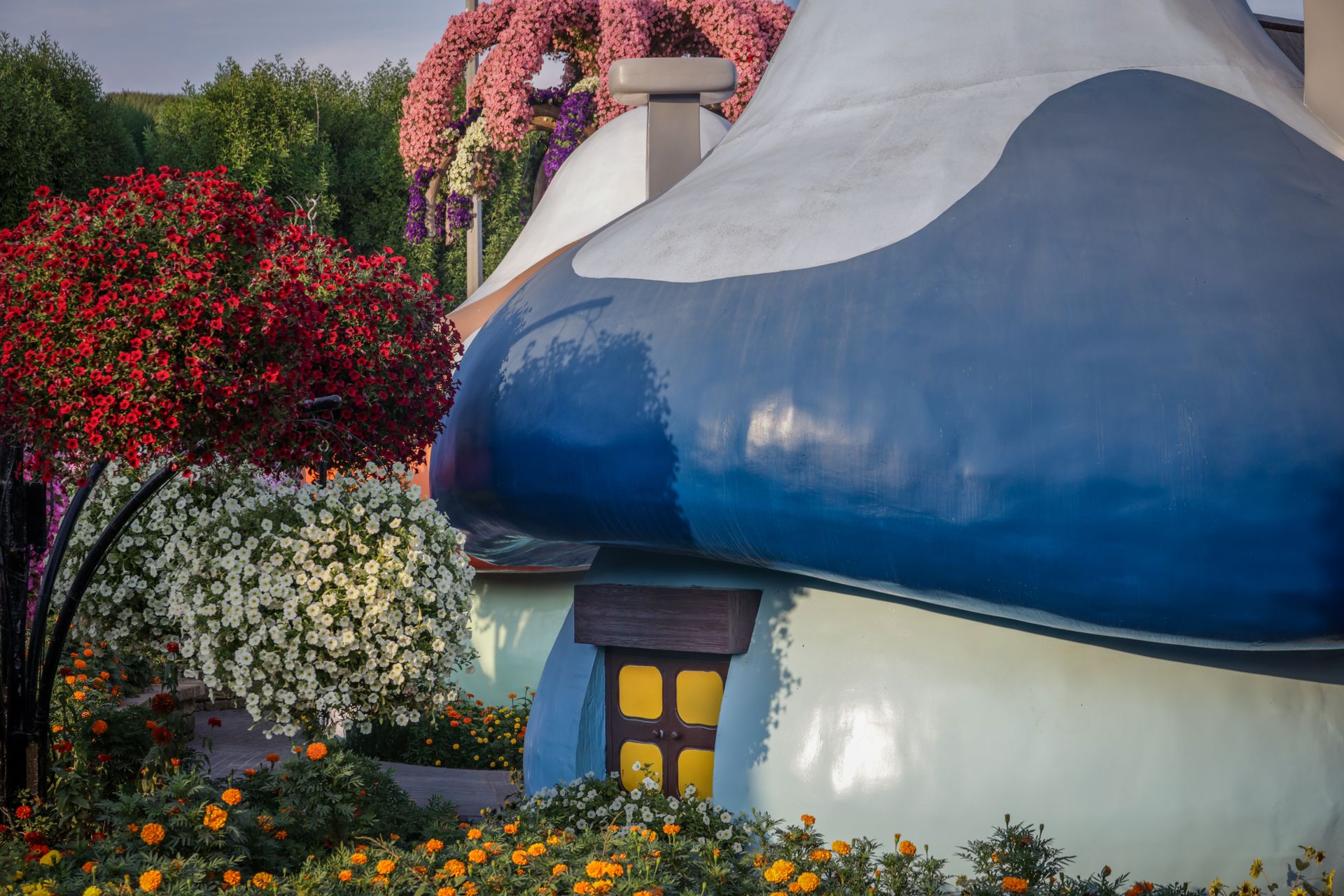 Charming mushroom house surrounded by colorful blooming flowers in a vibrant garden setting.