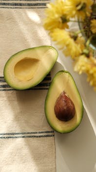 Close-up of avocado halves with a floral accent in warm natural light.
