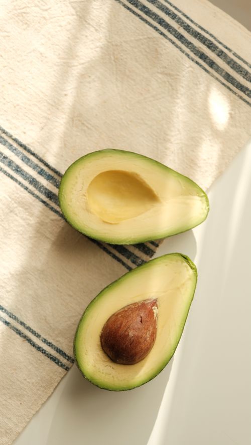 Free Top view of ripe avocado halves on striped kitchen cloth with natural lighting. Stock Photo
