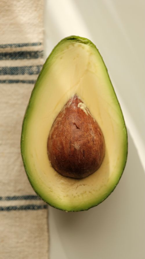 Free Close-up of a ripe avocado sliced in half showcasing its seed. Stock Photo