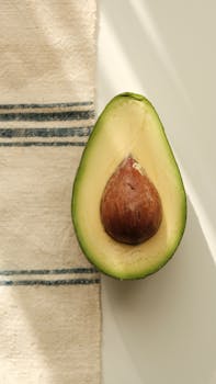A fresh avocado half placed on a rustic cloth, bathed in natural sunlight.