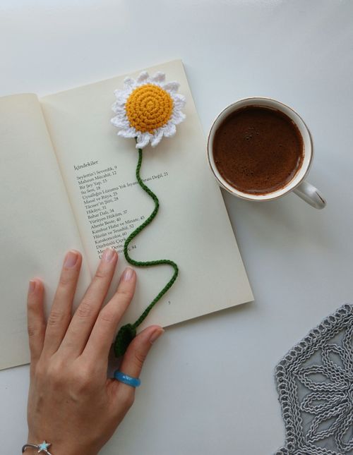 Free A crochet flower bookmark on an open book with coffee, embodying a relaxing reading moment. Stock Photo