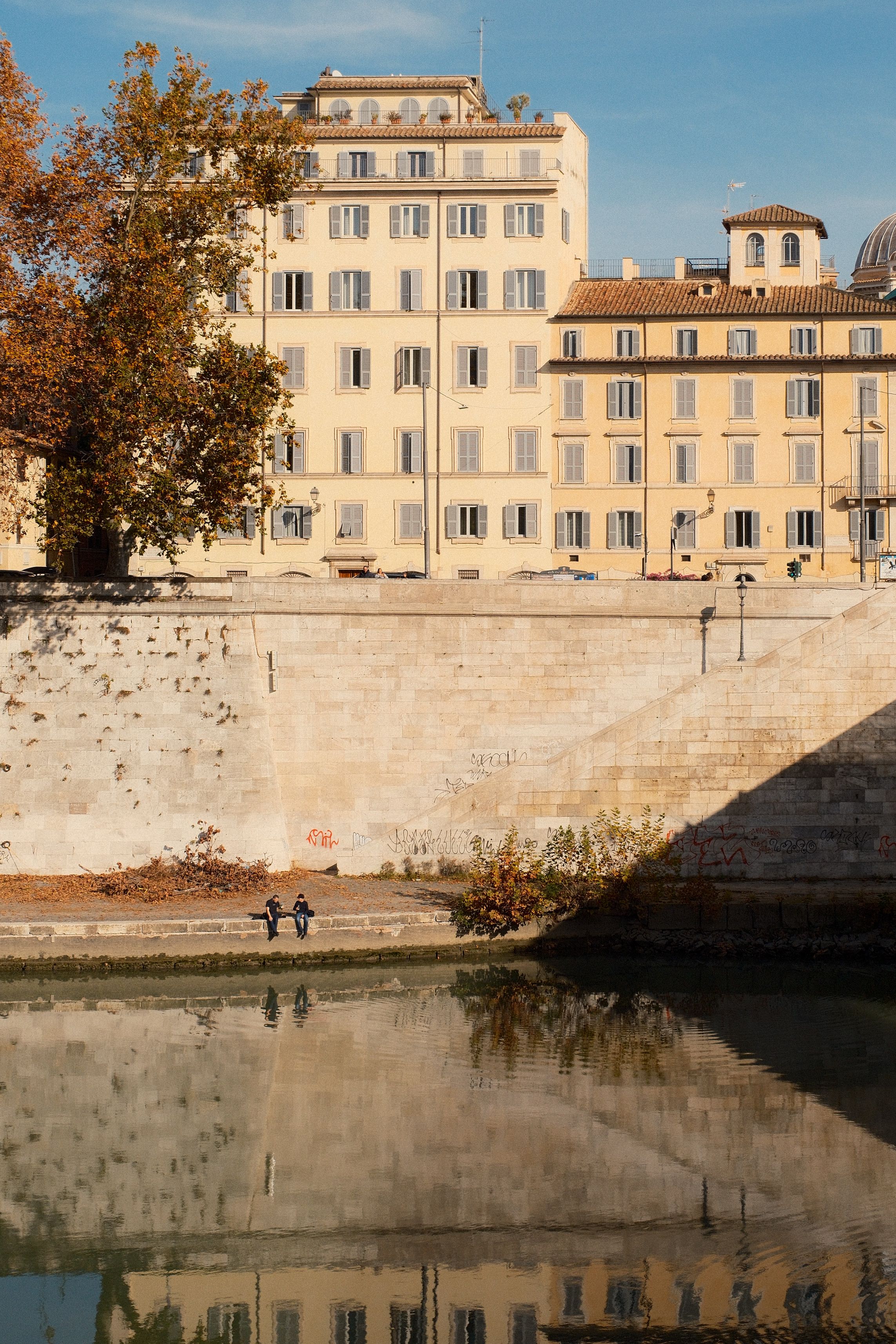 Charming view of riverside architecture in Rome with reflections and autumn ambiance.
