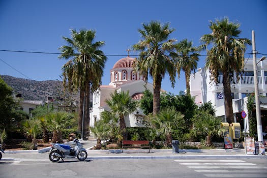 Greek church with palm trees on a sunny day in Crete. Motorbike passing by.