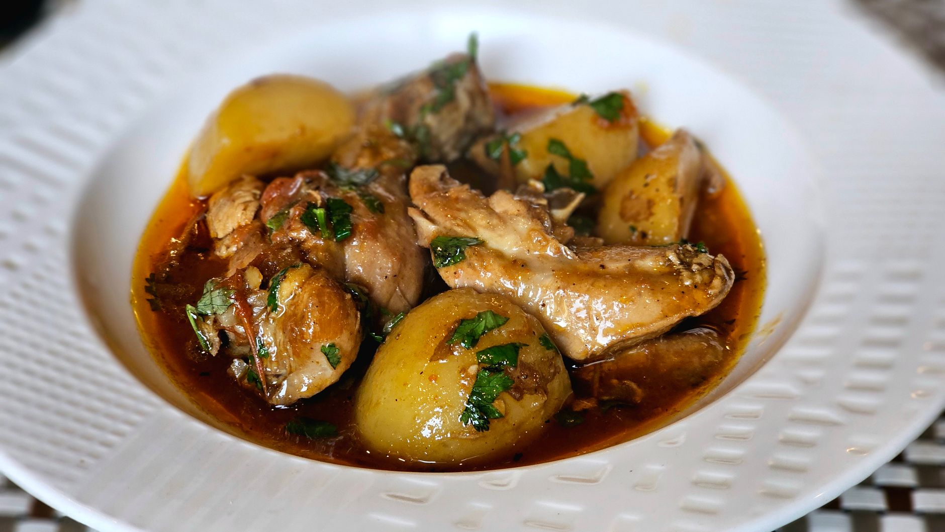 Cooked rabbit dish with vegetables and herbs on a plate