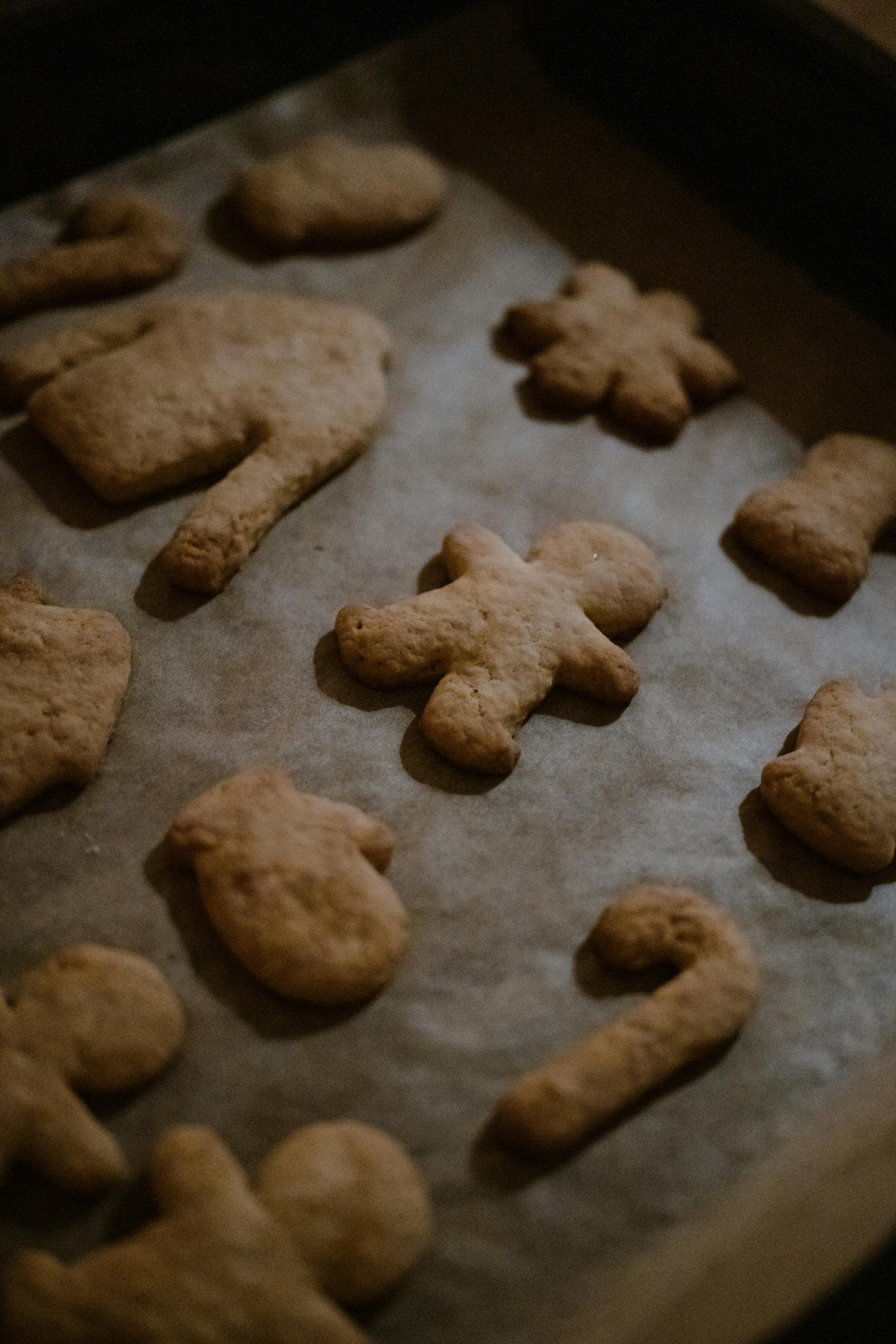 Freshly baked holiday cookies in festive shapes placed on a baking sheet.