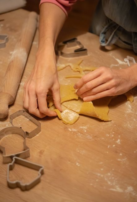 Close-up of hands shaping dough with cookie cutters on a wooden surface.