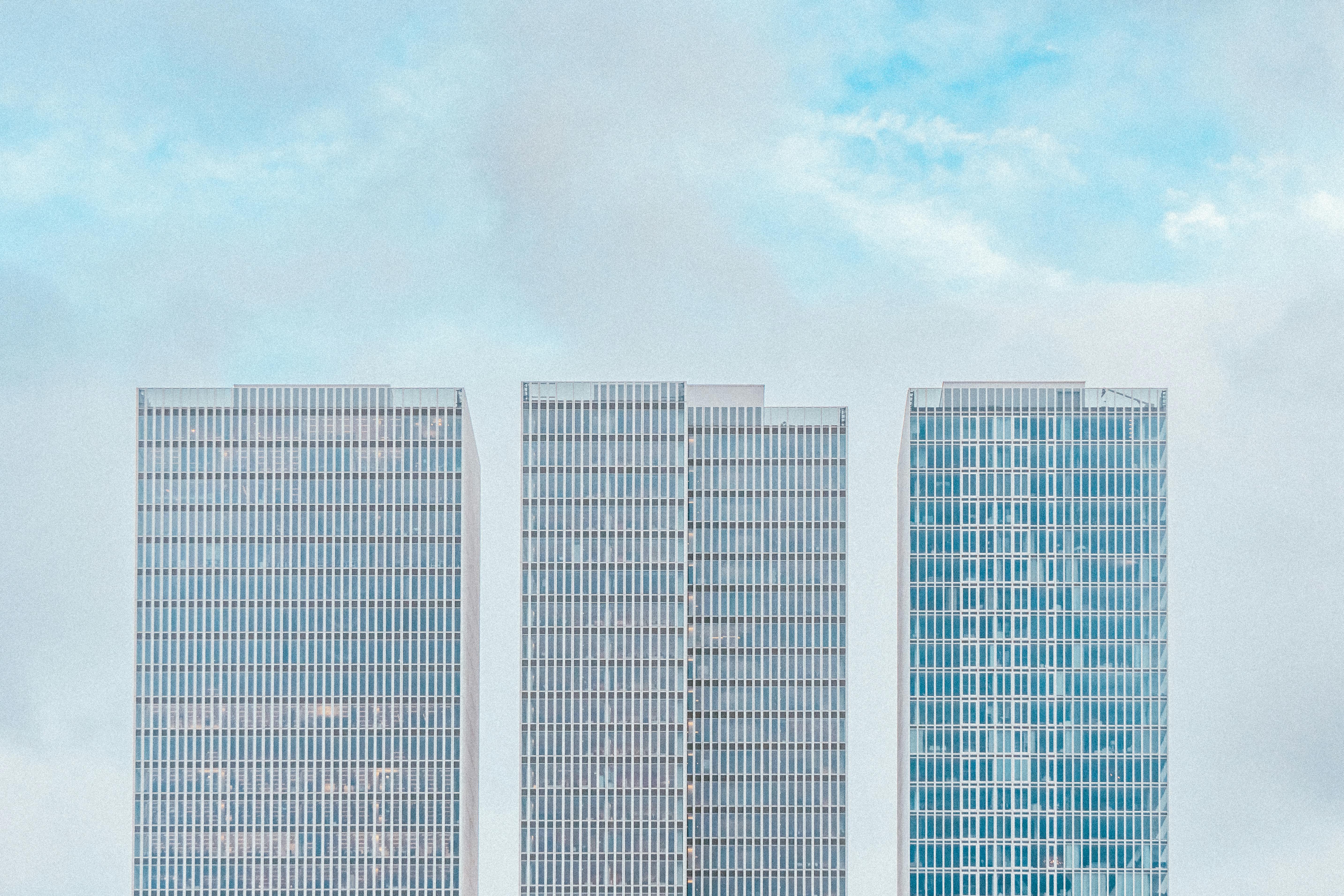 Symmetrical skyscrapers in Rotterdam with glass façades against a bright sky.
