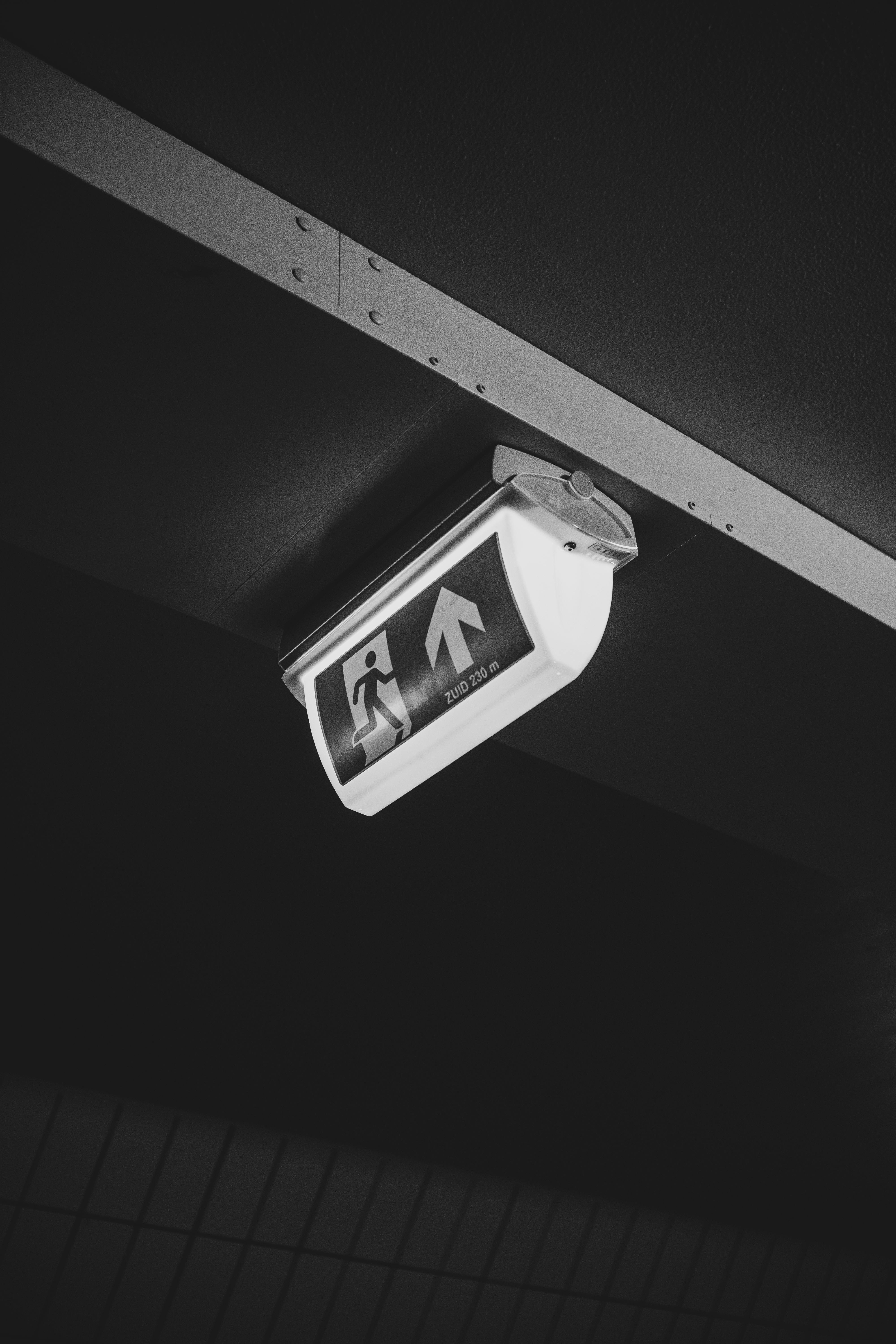 免費 一張黑白照片，畫面中隧道內的緊急出口標誌與背景形成鮮明對比，引人注目。 圖庫相片