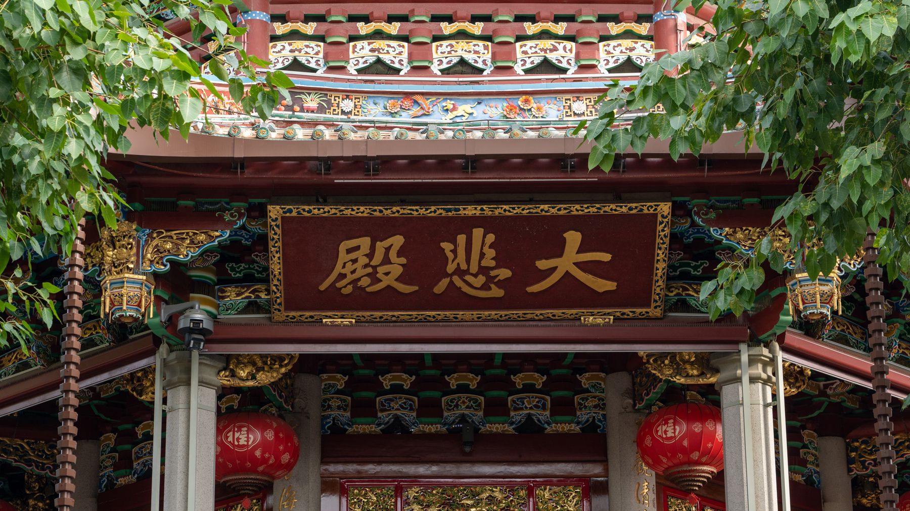 Intricate details of a traditional Chinese temple entrance with red lanterns and gold accents.
