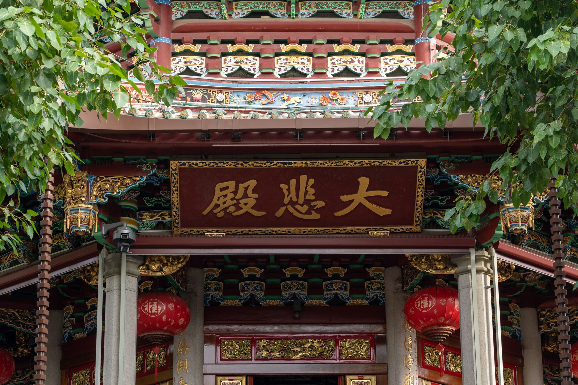 Intricate details of a traditional Chinese temple entrance with red lanterns and gold accents.