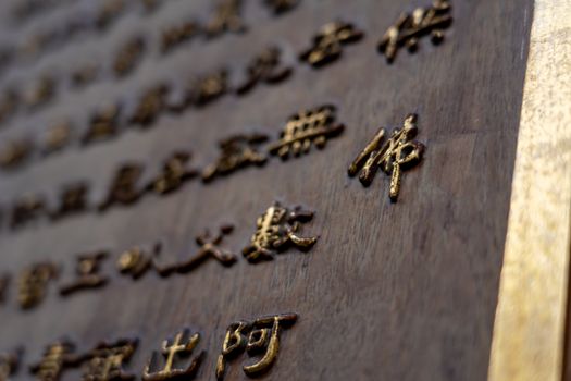 Detailed view of gold Chinese characters embossed on a wooden surface, showcasing traditional calligraphy.