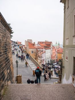A bustling street in Prague filled with tourists, showcasing historic architecture and vibrant city life.