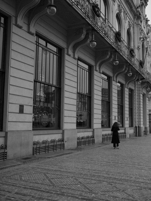 Free Black and white photo of classic European architecture with a solitary person, evoking nostalgia. Stock Photo