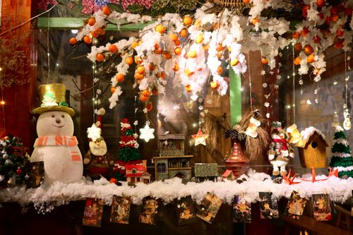Free A colorful, festive window display featuring a snowman, Christmas ornaments, and holiday decorations. Stock Photo