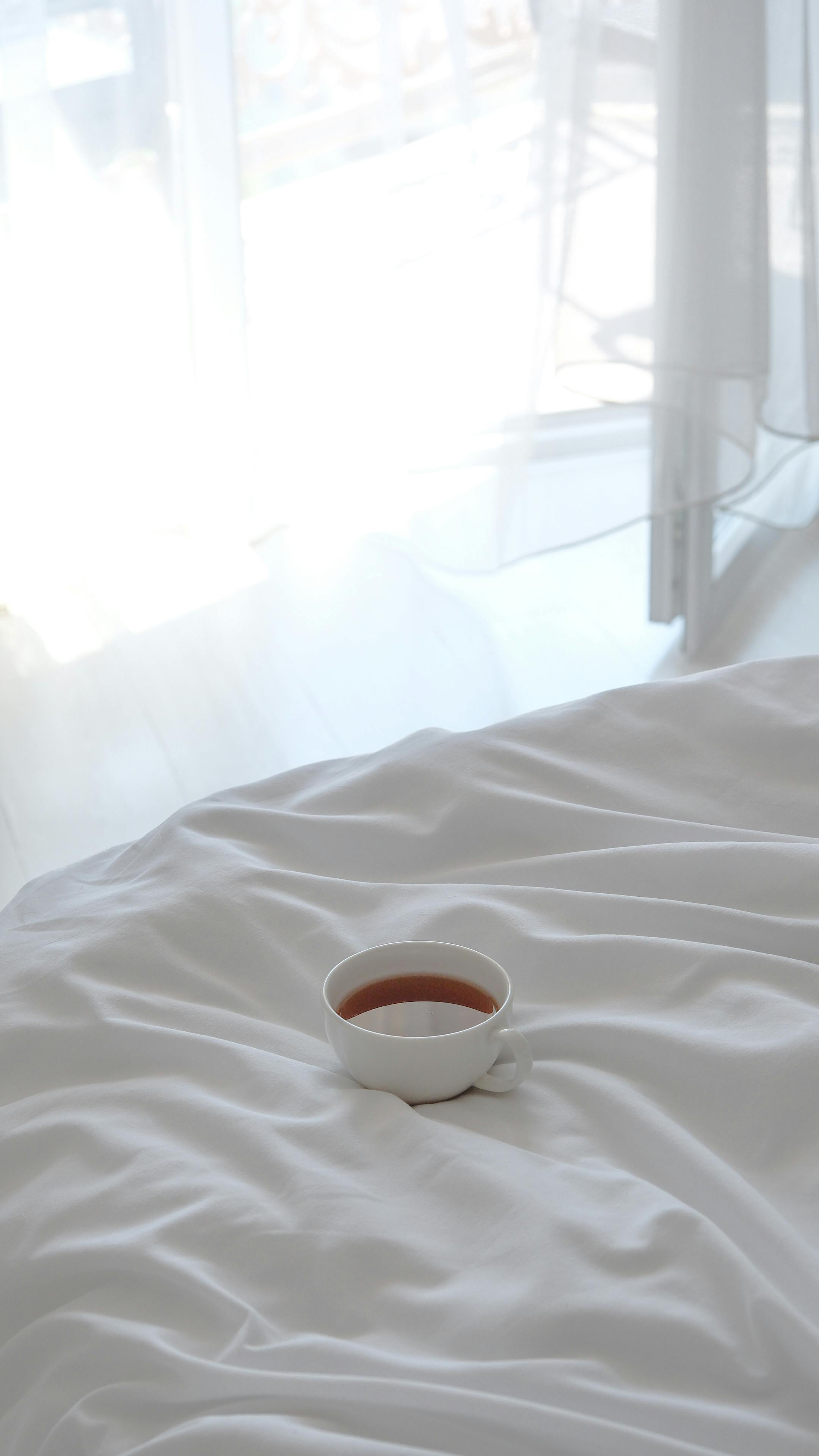 Lit douillet avec une tasse de thé, symbolisant un environnement de sommeil serein