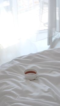 A cup of tea on a white bed in a softly lit room in Istanbul, capturing a moment of tranquility.