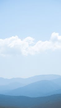 Layered blue mountains under fluffy clouds, creating a calming scenic view.