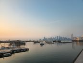 Doha skyline viewed from waterfront with boats at sunrise, showcasing Qatar's blend of tradition and modernity.
