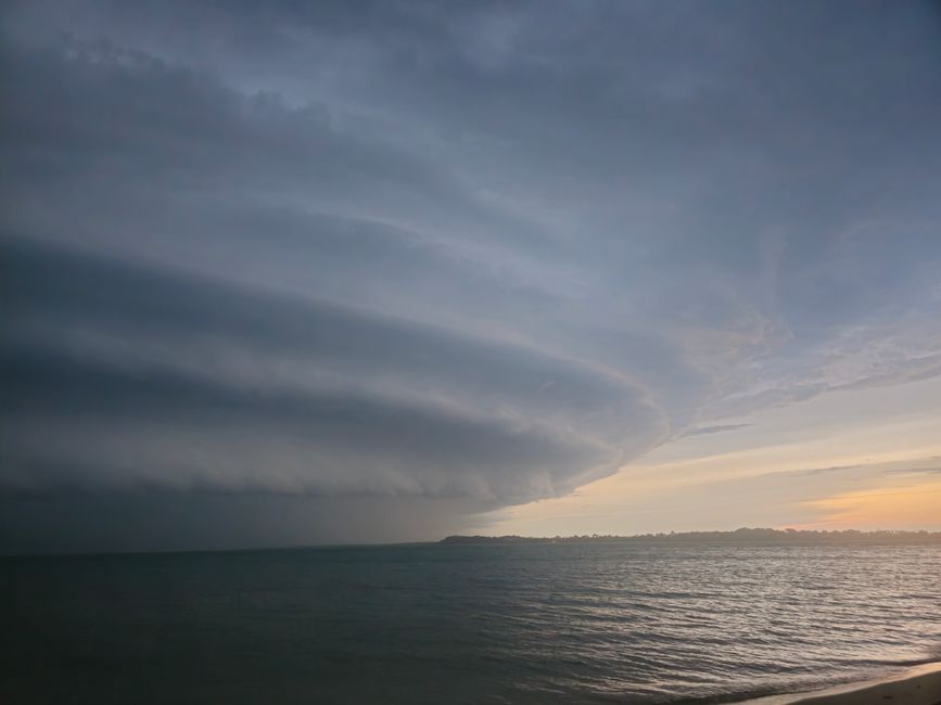 Striking view of layered storm clouds over ocean waters during a sunset.