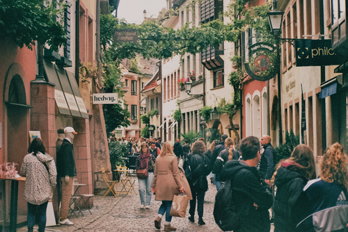 Free Cobblestone street in Freiburg im Breisgau bustling with pedestrians enjoying a bright day. Stock Photo