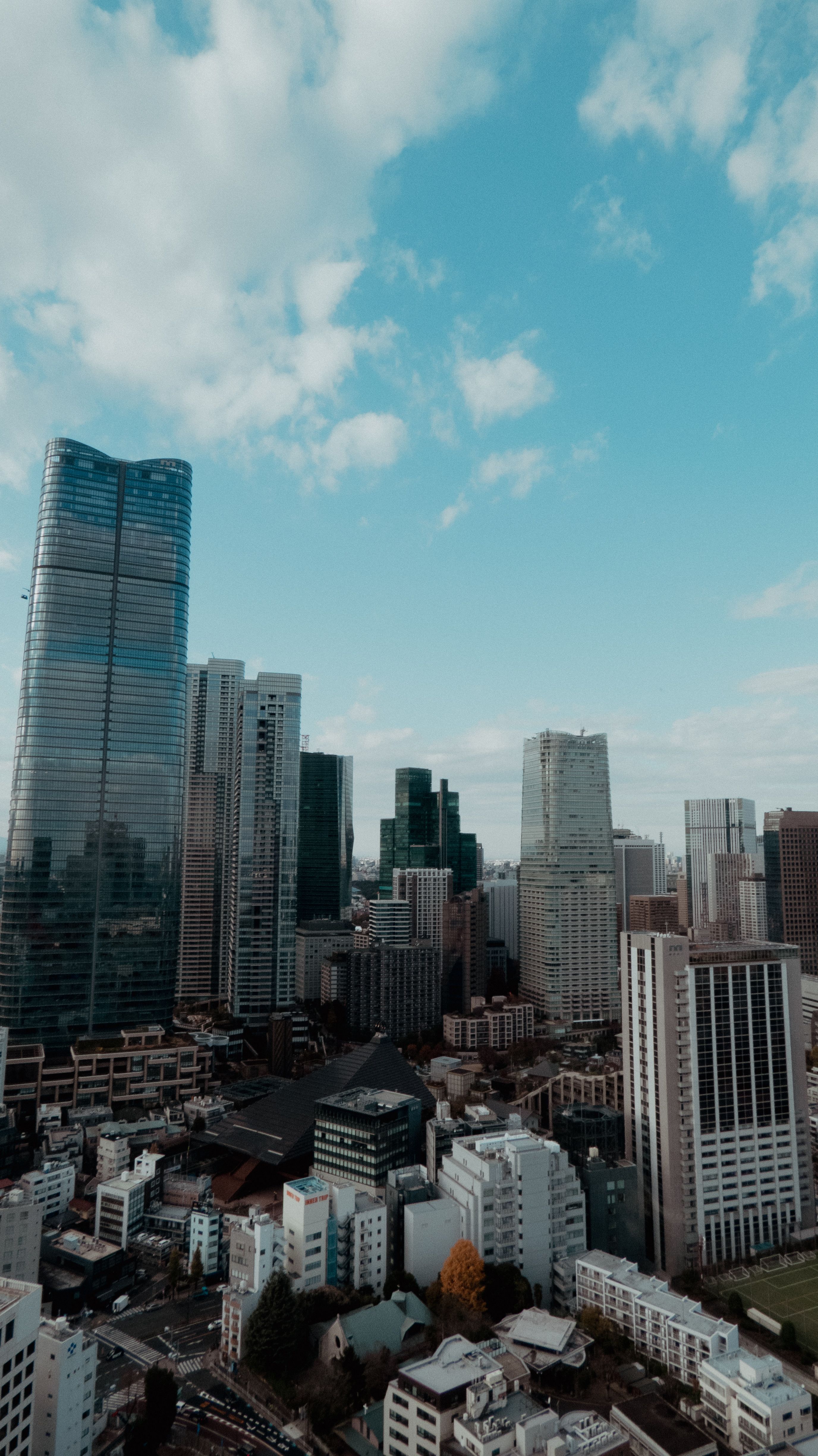 Aerial view of modern city skyline with skyscrapers against blue sky.