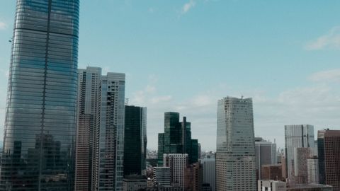 Aerial view of modern city skyline with skyscrapers against blue sky.
