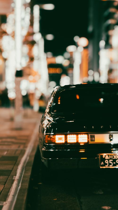 Free Retro car captured at night on a bustling, illuminated city street. Stock Photo