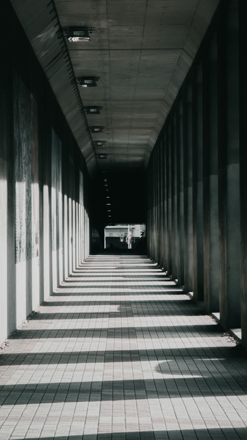 Free An empty, shadowed corridor with geometric patterns and modern architecture. Stock Photo