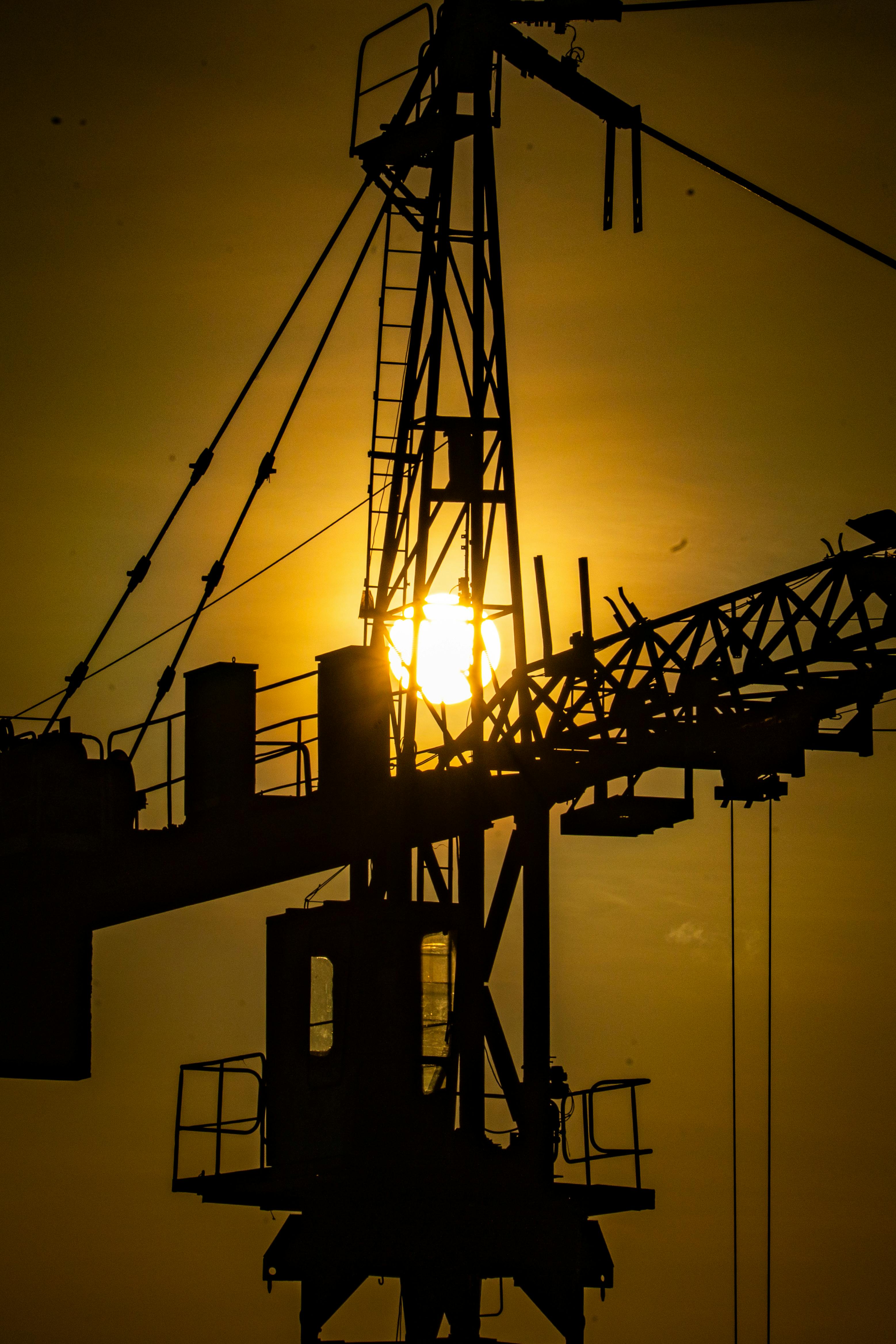 Industrial crane silhouette against golden sunset, symbolizing construction progress.