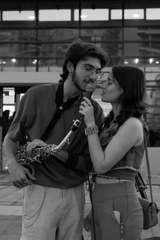 A candid black and white photo of a street performance with two musicians sharing a moment.