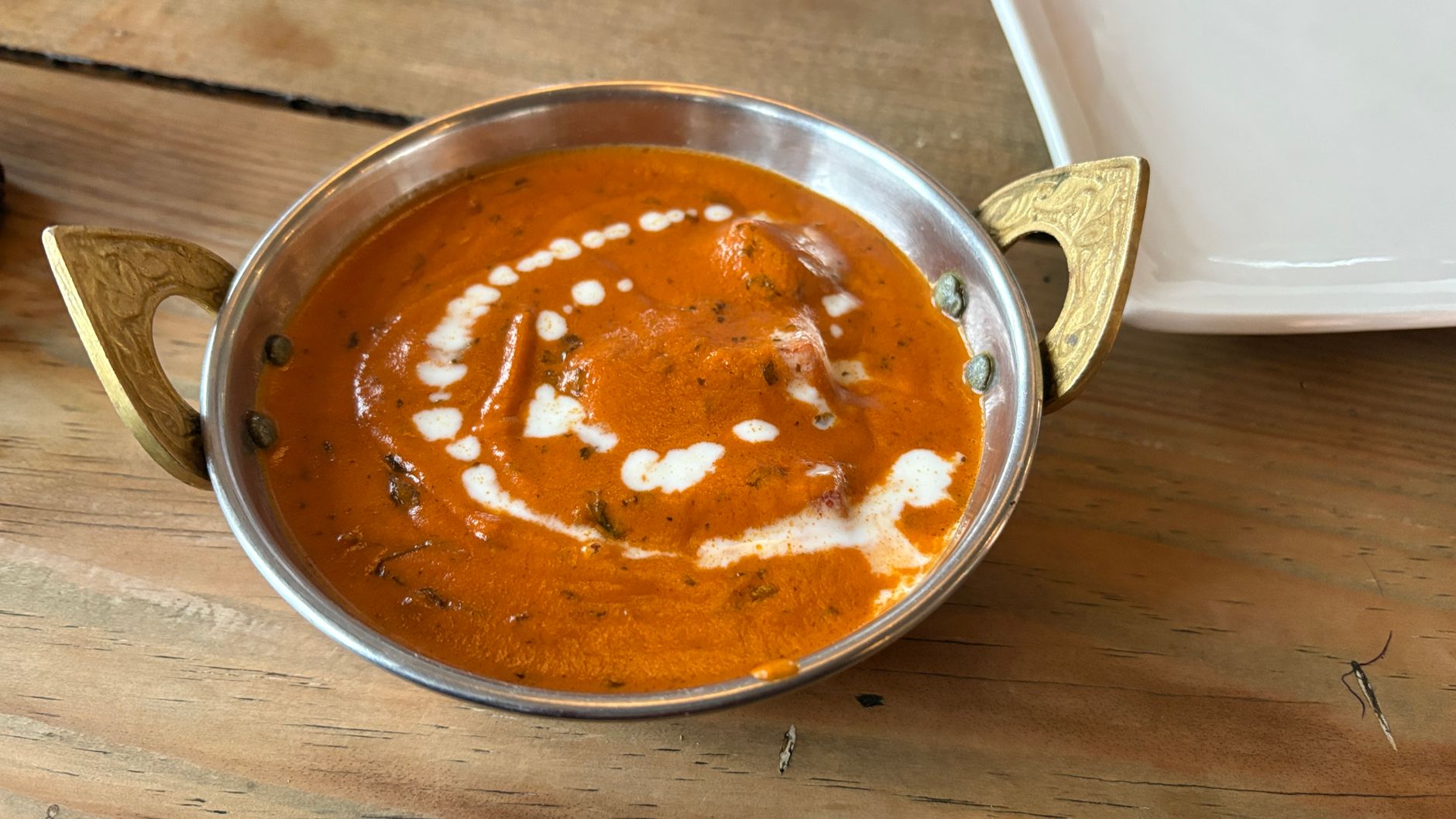 Kremalı domates sosunda, taze kişniş serpiştirilmiş, baharatlı tereyağlı Hint tavuğu yemeği, yanında bir kase basmati pilavı ve naan ekmeği ile.