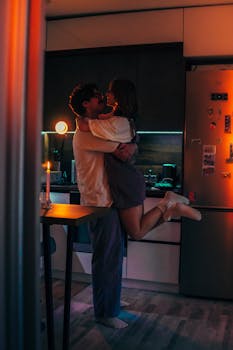A couple shares a romantic moment in a warmly lit kitchen, capturing the essence of love and intimacy.