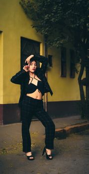 Stylish woman in chic outfit posing on a city street during the day, showcasing fashion and confidence.